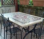 Tavolo con sedie in ferro con mosaico sotto  una veranda